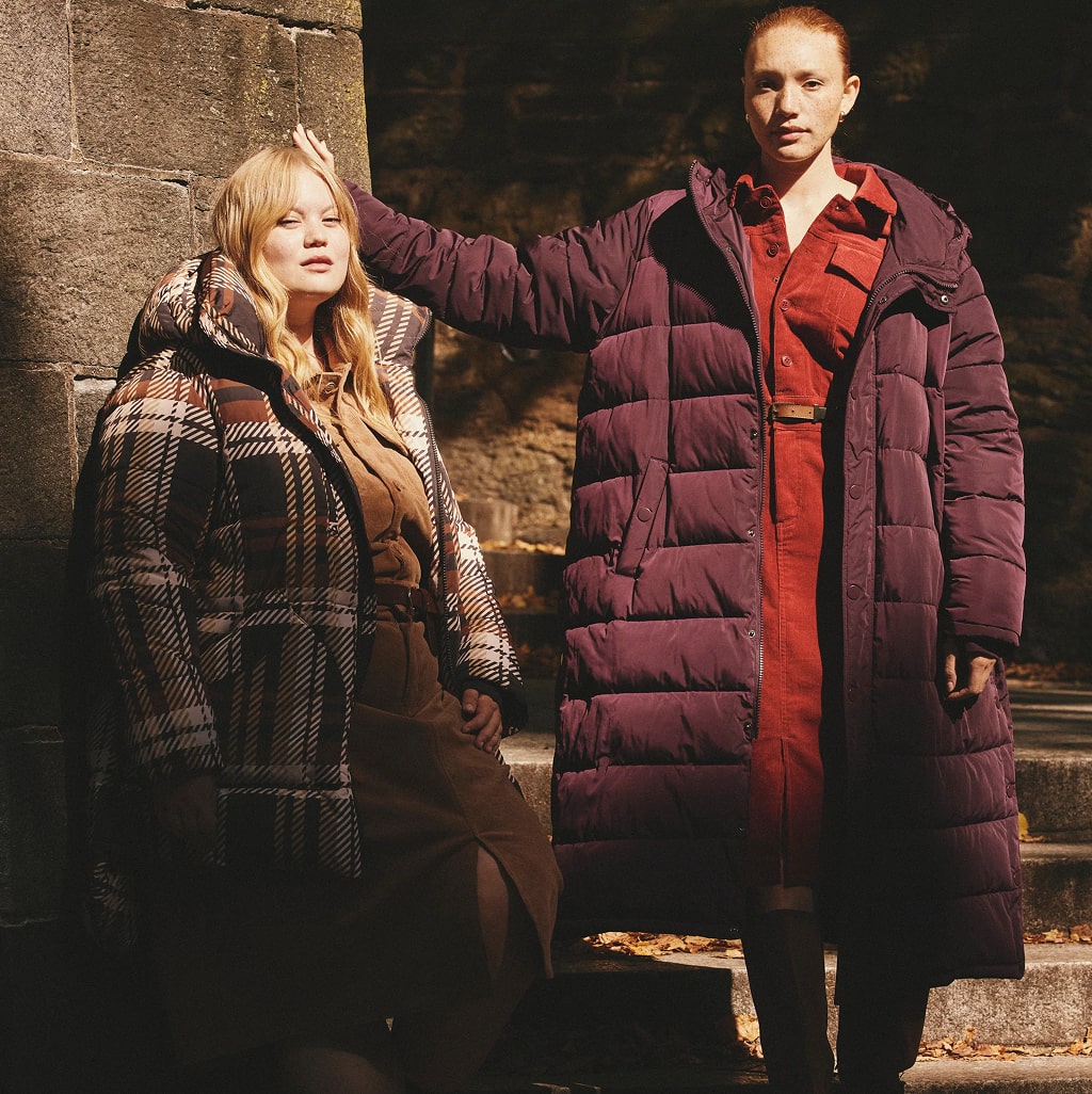 Two women in plaid and burgundy winter coats posing outdoors