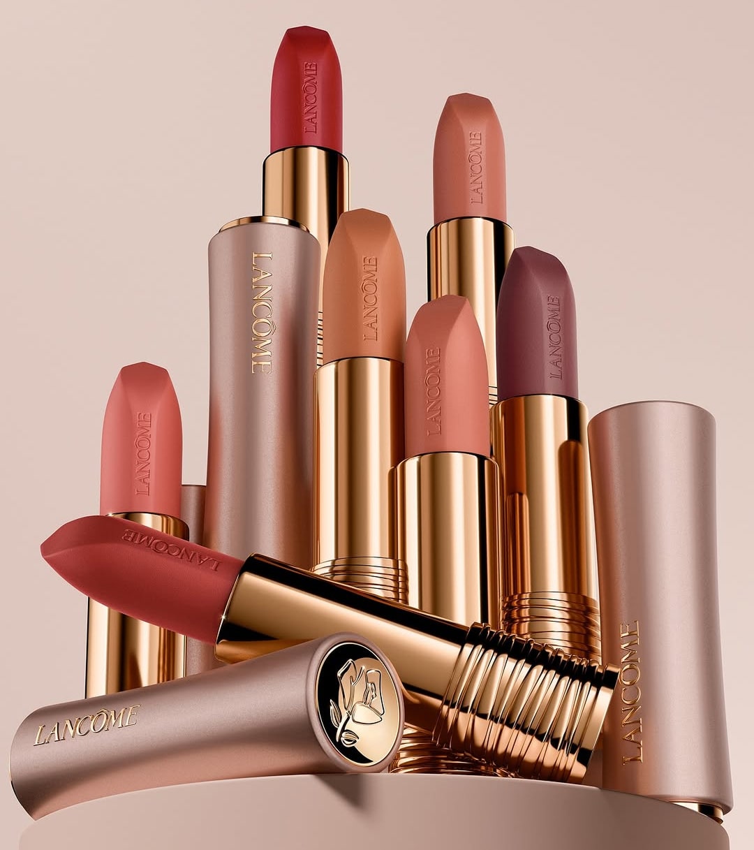 Group of lipsticks in pink, red, and nude shades styled in an artistic stacked composition.